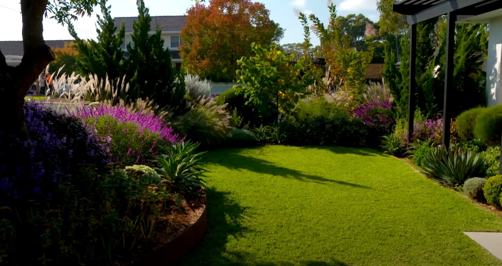 Perfectly manicured lawn with colorful flower borders and mature trees creating a stunning residential landscape