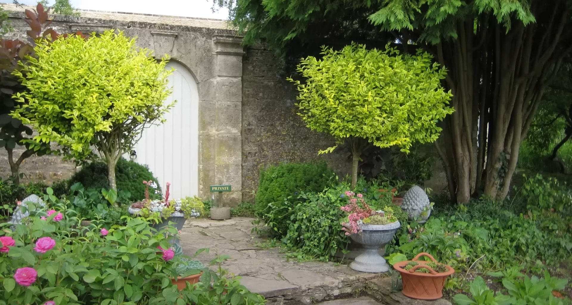 Traditional Garden Design Classic garden entrance with stone archway, decorative planters, and traditional English garden design